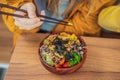 Woman eating Raw Organic Poke Bowl with Rice and Veggies close-up on the table. Top view from above horizontal Royalty Free Stock Photo