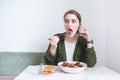 woman eating salad and talking on the phone in a restaurant on the background of a light wall Royalty Free Stock Photo