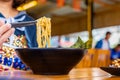 Woman eating a spicy ramen Japanese noodle soup in a black color ramen bowl Royalty Free Stock Photo