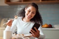 Woman eating sushi and using her cellphone. Young woman sending a text on her smartphone while eating seafood. Happy Royalty Free Stock Photo