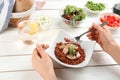 Woman eating tasty rice with meat and vegetables at white wooden table, closeup Royalty Free Stock Photo