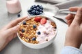 Woman eating tasty homemade granola with yogurt and berries at grey table. Healthy breakfast Royalty Free Stock Photo