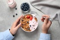 Woman eating tasty homemade granola with yogurt and berries at grey table. Healthy breakfast Royalty Free Stock Photo