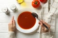 Woman eating tasty tomato soup on white wooden background Royalty Free Stock Photo