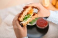 Woman eating tasty waffles with fried egg and chicken, closeup