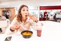 Woman eating too hot and peppery soup in an Asian fast food restaurant. Concept of spices in Oriental cuisine