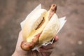 Woman eating typical grilled German Bratwurst sausage street food with bread roll bun and mustard on the go