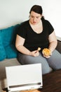 Woman eating unhealthy food watching series online Royalty Free Stock Photo