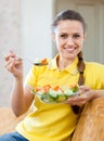 Woman eating veggie salad on sofa