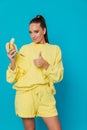 Woman eating yellow bananas in ears on blue background Royalty Free Stock Photo