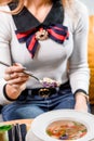 Woman eats broth with quail eggs, herbs, carrots and other vegetables in a white plate on a yellow set on the table. Royalty Free Stock Photo