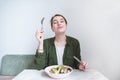 Woman eats a delicious salad. A sweet girl sits at the table, eats a plate salad and delights Royalty Free Stock Photo