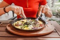 woman eats fried eggs with bacon in a frying pan in a street restaurant. The concept of a fat breakfast with a lot of