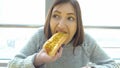 Woman eats a hot dog at a fast food cafe. Royalty Free Stock Photo