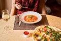 Woman eats Italian pasta with tomato, meat. Close-up spaghetti Bolognese wind it around a fork with a spoon. Parmesan Royalty Free Stock Photo