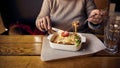 A woman eats lasagnia with cheese and a Behamel sauce from a white ceramic plate located next to a glass of water on the table Royalty Free Stock Photo