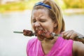 A woman eats meat cooked over an open fire. The summer Bank of the river Royalty Free Stock Photo