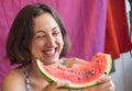 A woman eats a watermelon and laughs