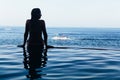 Woman at edge of infinity swimming pool with sea view Royalty Free Stock Photo