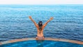 Woman at edge of infinity swimming pool with sea view Royalty Free Stock Photo