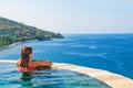 Woman at edge of infinity swimming pool with sea view Royalty Free Stock Photo