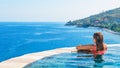 Woman at edge of infinity swimming pool with sea view Royalty Free Stock Photo