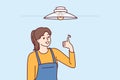 Woman electrician showing thumbs up after fixing chandelier or replacing light bulb under ceiling Royalty Free Stock Photo