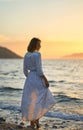 Woman in dress standing at the sea beach. Nature and beauty concept. Girl silhouette at sunset Royalty Free Stock Photo