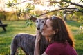 Woman is embracing her old dog with love. Pet owner and Spanish greyhound together outdoors