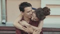 Woman embracing man in city in slow motion. Couple sitting on bench outdoors.