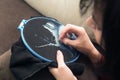 A woman embroiders a picture with threads