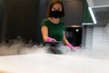 Woman employee cleaning company blows vapor out of steam generator. Steam cleaning process for kitchen furniture.