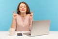 Woman employee sitting at workplace in anticipation of pleasant business event, crossing her fingers and wishing for good luck