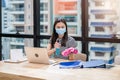 Woman employee wearing face mask preparing alcohol spray and cloth for cleaning on wooden desk in the office Royalty Free Stock Photo