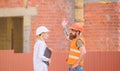 Woman engineer and bearded brutal builder discuss construction progress. Construction project management. Building