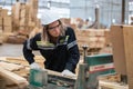 woman engineer carpenter wearing safety uniform and hard hat working on wood cutting electric machines at workshop manufacturing Royalty Free Stock Photo