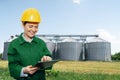 Woman engineer with a digital tablet on a background of agricultural silos Royalty Free Stock Photo