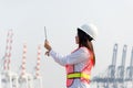 The women engineer holding laptop and working with container Cargo freight ship in shipyard at dusk for Logistic Import Export bac Royalty Free Stock Photo