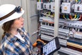 Woman engineer inspects switchboard while holding tablet. Panel check. Royalty Free Stock Photo
