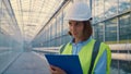 Woman engineer making notes analysing production data in modern glasshouse