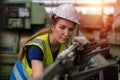 Woman engineer wear hardhat working at machine in factory. female technician control metalwork lathe industrial Royalty Free Stock Photo