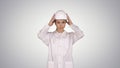 Woman engineer in white robe and white hard hat walking on gradient background. Royalty Free Stock Photo