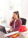 Woman engineer working on laptop and talking on phone Royalty Free Stock Photo