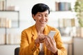 Woman engrossed in websurfing applications on cellphone at workplace indoors Royalty Free Stock Photo