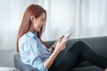 Woman enjoy with content streaming movies or social media application on digital tablet sitting on sofa at home. Royalty Free Stock Photo