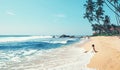 Woman enjoy with ocean surf sitting on the lonely tropical beach under the palm trees Royalty Free Stock Photo