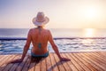 Woman enjoying beach vacation holidays, relaxing at infinity swimming pool of luxury resort hotel, looking at sunset. Warm Royalty Free Stock Photo