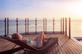 Woman enjoying beach vacation holidays, relaxing by luxury resort hotel swimming pool on deckchair lounger, looking at sunset. Royalty Free Stock Photo