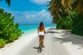 Woman Enjoying a Bicycle Ride Along a Scenic Tropical Beach. Royalty Free Stock Photo