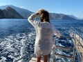 Woman enjoying cruise on luxury white yacht. Amazing ocean view around. Wealth travel concept, private boat tour. View from behind